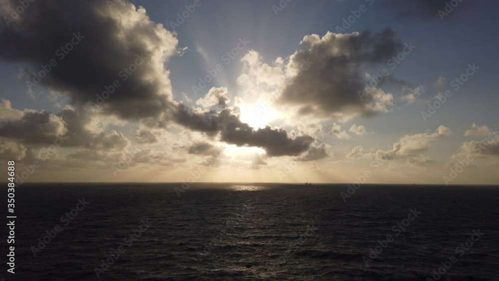 Sun light passing through clouds in the middle of the ocean. Offshore sunrise.
