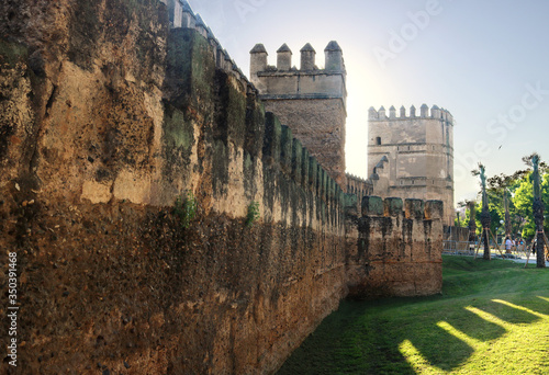 view of a the castle and the wall of the old city of Seville, with the battlements of the towers and  the fortress in a sunny day photo