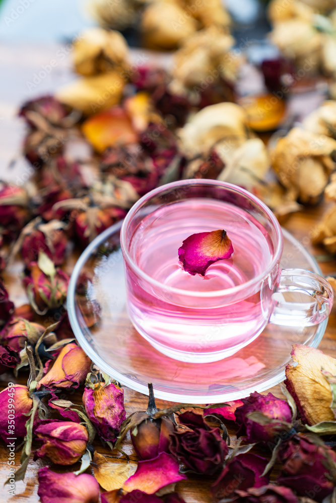 Organic tea rose made from tea  rose petals in a glass bowl on the wooden rustic background around with dry rose petals