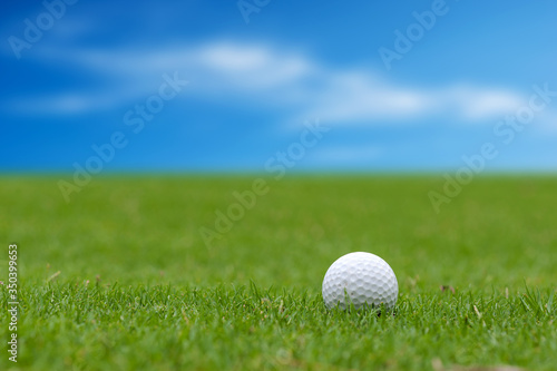 White Golf ball on green course to be shot on blurred beautiful landscape of golf course in bright day time with copy space. Sport, Recreation, Relax in holiday concept