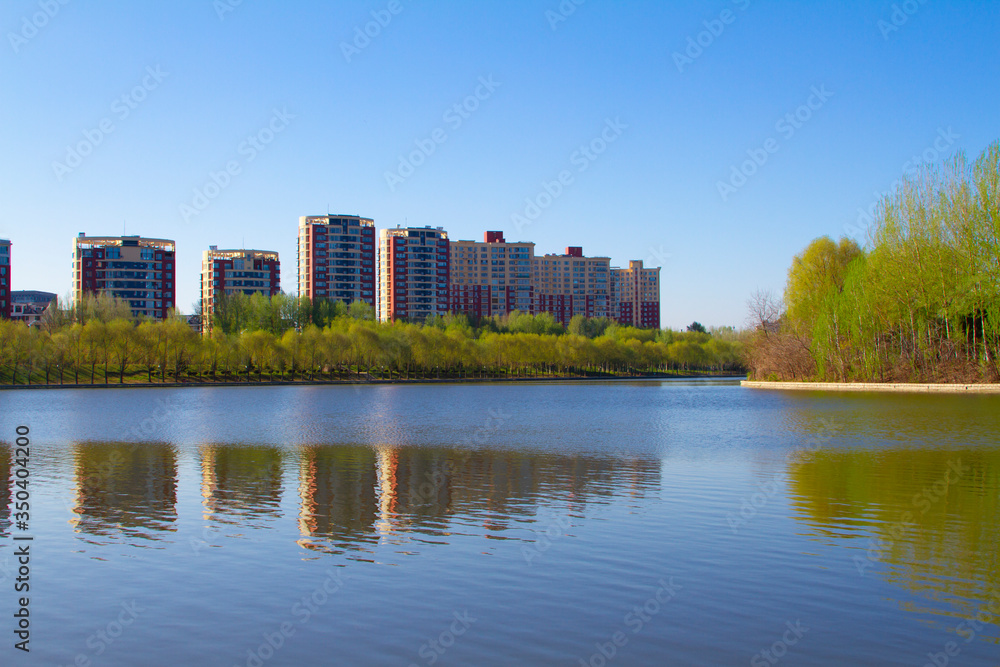 Modern apartment buildings by a lake with shadows in the water mirror reflection Spring