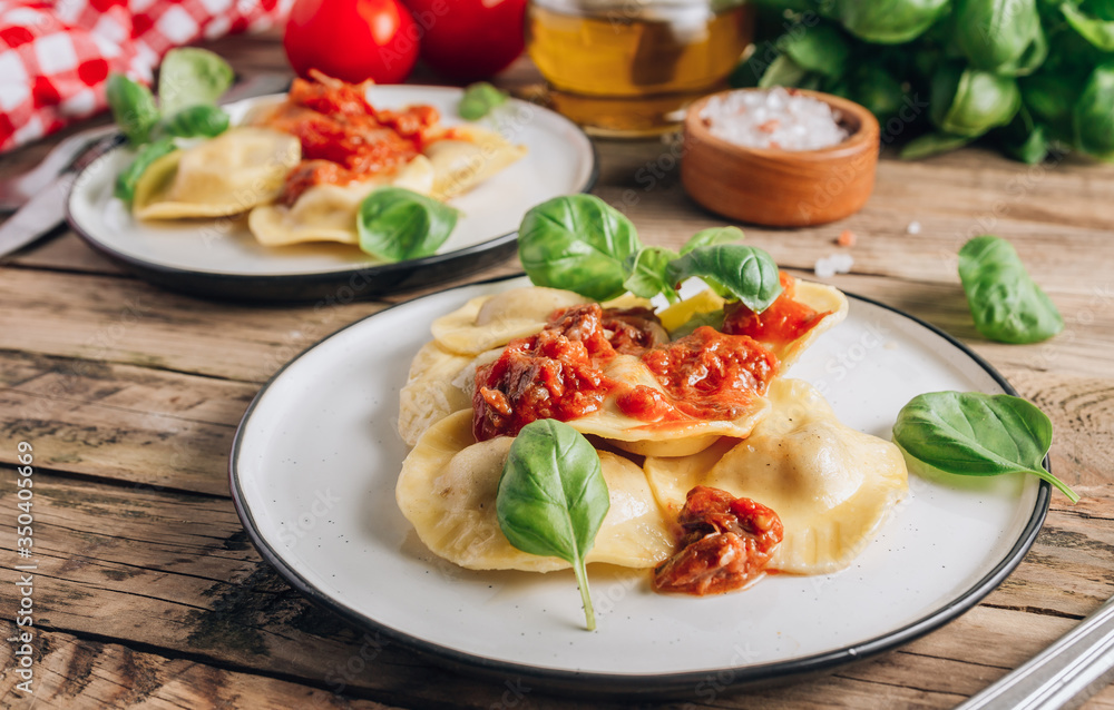 Italian ravioli with meat tomato sauce and basil leaves with on a white dishes on an old rustic background. Italian ravioli with meat tomato sauce and basil leaves with on a white dishes on an old rustic background.