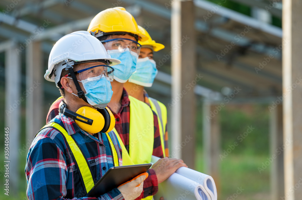 Engineer wearing protective mask to Protect Against Covid-19 working on checking and maintenance in solar power plant,Solar power plant,Science solar energy. Engineer wearing protective mask to Protect Against Covid-19 working on checking and maintenance in solar power plant,Solar power plant,Science solar energy.