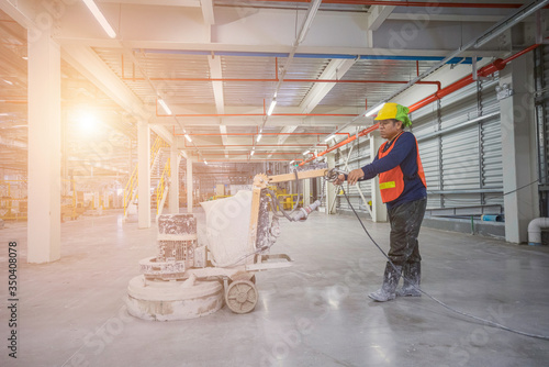 Construction worker using machine polishing surface floor smoothing and finishing hardener or epoxy concrete in the fact