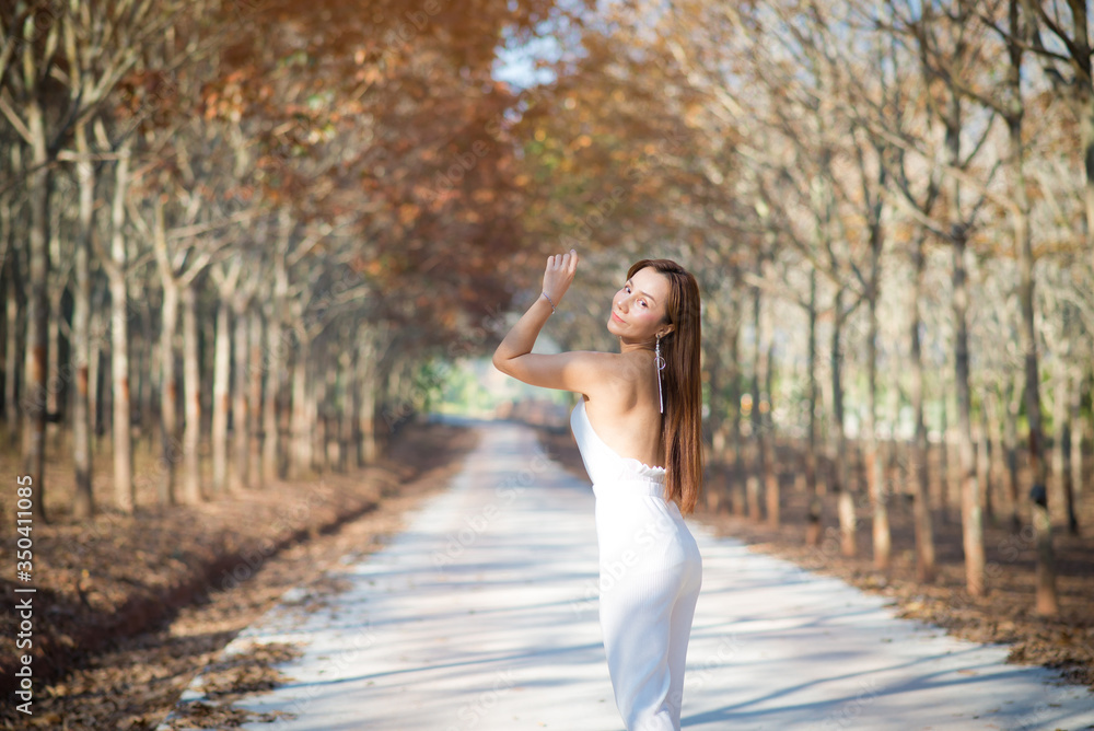 Beautiful happy asian woman admiring nature with rubber tree in summer.