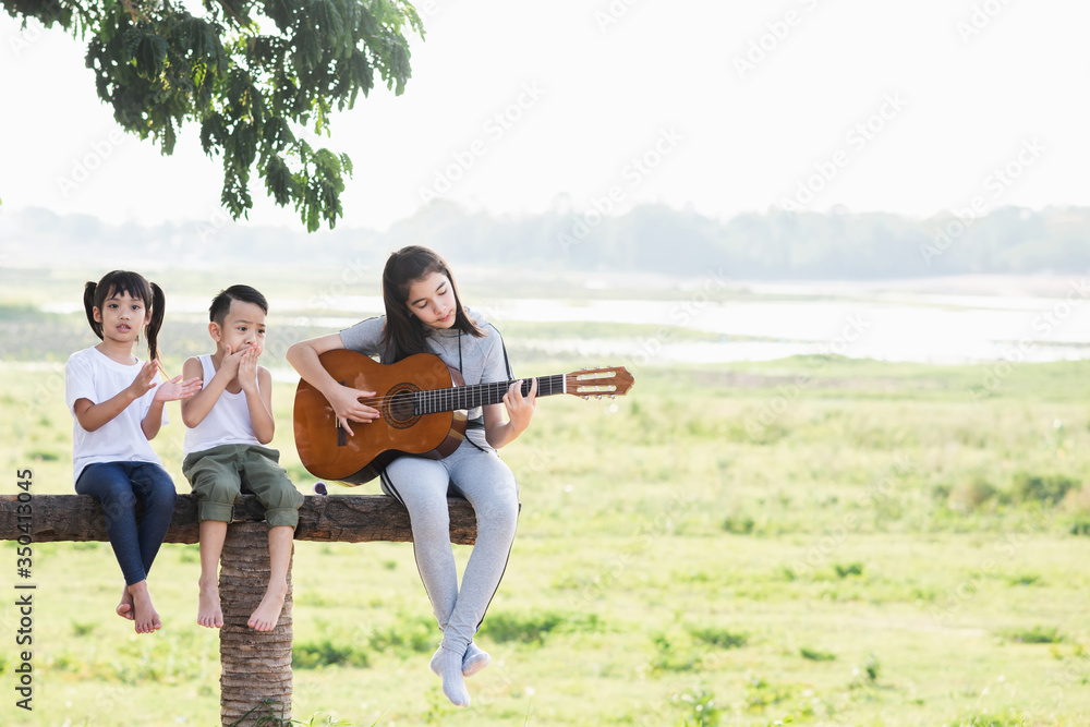 Fototapeta premium Children playing guitar at sunset.