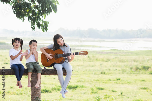  Children playing guitar at sunset.