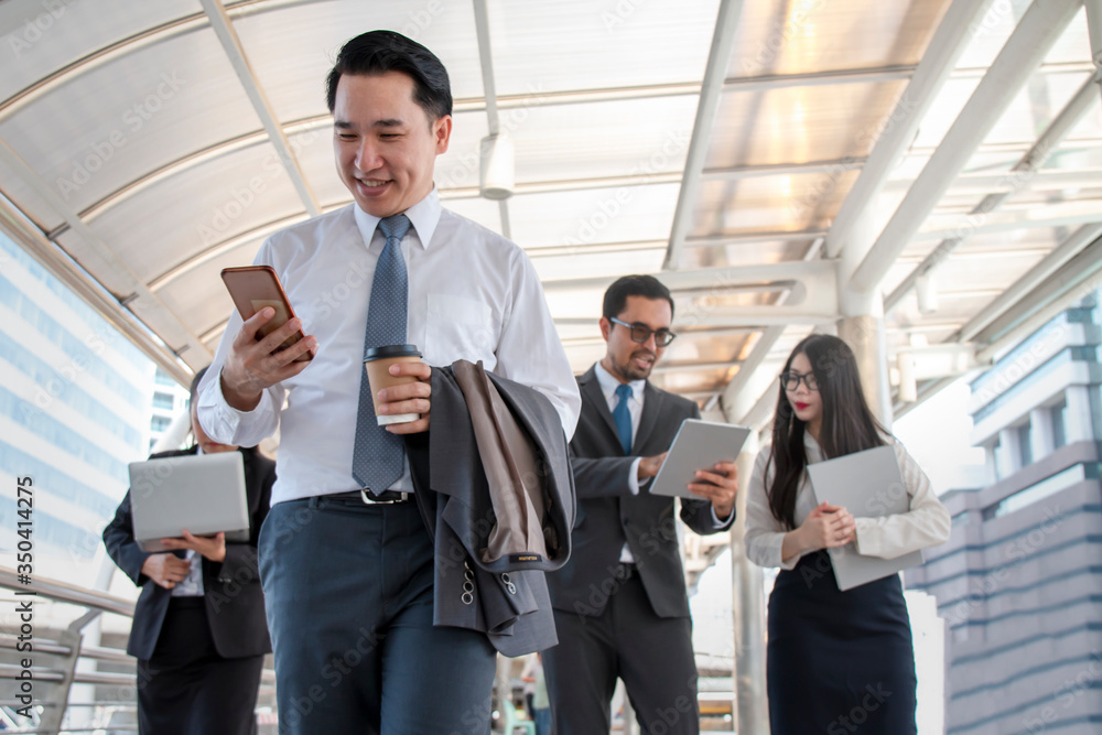 Businessmen who are walking and looking at mobile phones and the Businessmen who are walking and looking at mobile phones and the