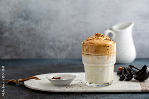 Dalgona coffee or whipped instant coffee. New popular food and drink trend. Light background, one glass with copy space photo