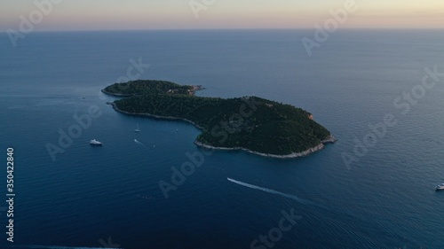 Aerial view of small island archipelago in blue Adriatic sea at sunset near Dubrovnik, Croatia. Croatian rural natural landscape. Sailboats floating on water.