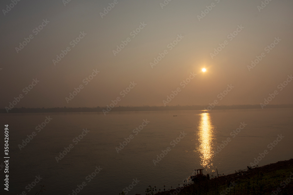Silhouette landscape riverside and reflection light surface water of Mekhong River and lighting of Sun in morning at Mukdahan, Thailand