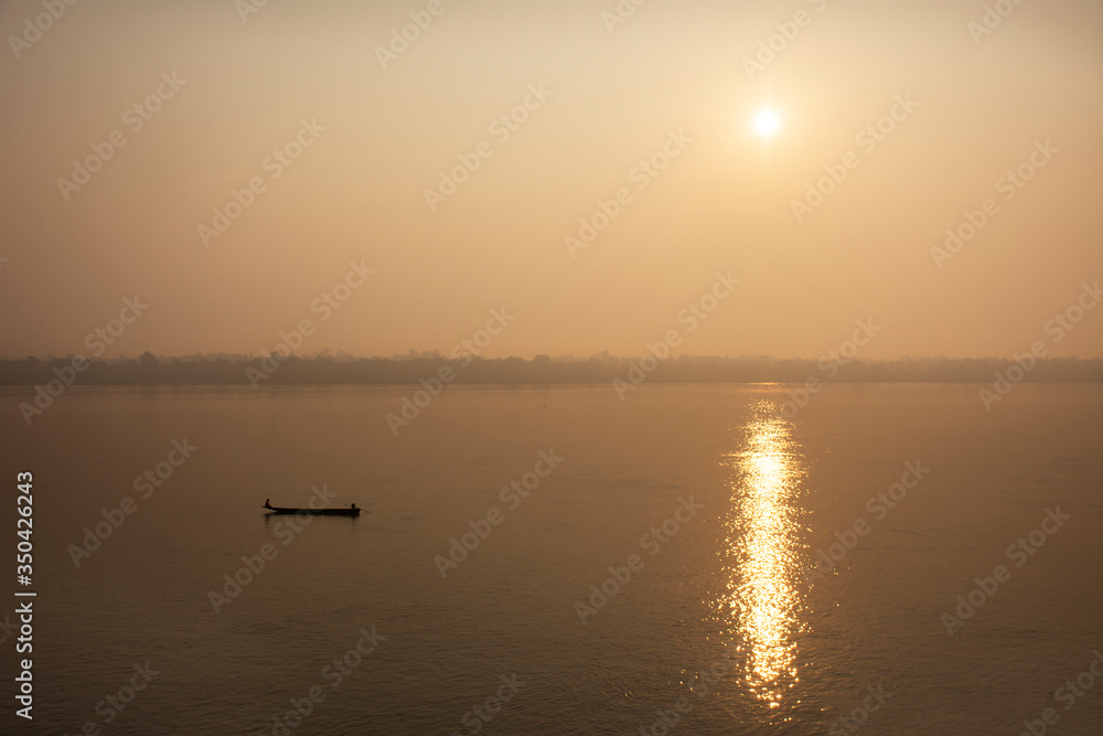 Thai and laos people riding long tail boat for catch fishing and reflection light surface water of Mekhong River and lighting of Sun in morning time at Mukdahan, Thailand