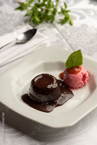 Chocolate petit gateau with strawberry red berries fruits and a leaf of mint