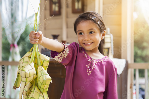 Muslim girl holding ketupats photo