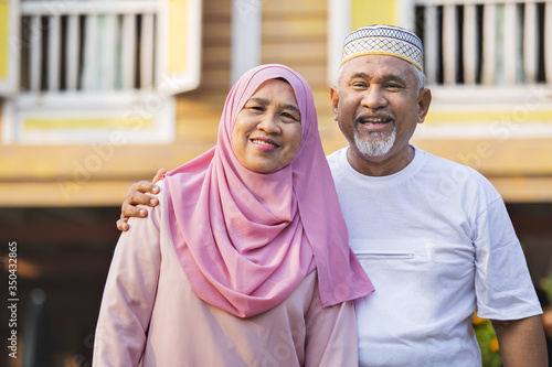 Senior couple standing in front of wooden house photo