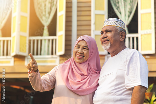 Senior couple standing in front of wooden house
