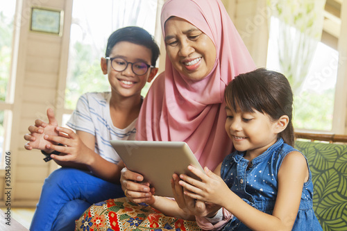 Grandmother and grandchildren using digital tablet