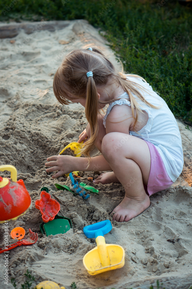 little girl with two ponytails in a white t-shirt and shorts plays in the playground little girl with two ponytails in a white t-shirt and shorts plays in the playground