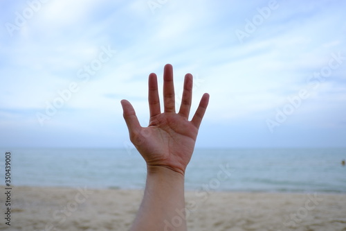 Human hand on the background of the ocean.  © Pongsakon