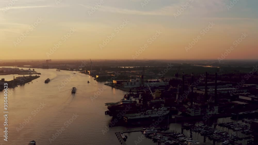 Beautiful colors of drone fliight at sunset over the industrial harbor Amsterdam - aerial over Ij river with freight container boats and cargo ships Beautiful colors of drone fliight at sunset over the industrial harbor Amsterdam - aerial over Ij river with freight container boats and cargo ships