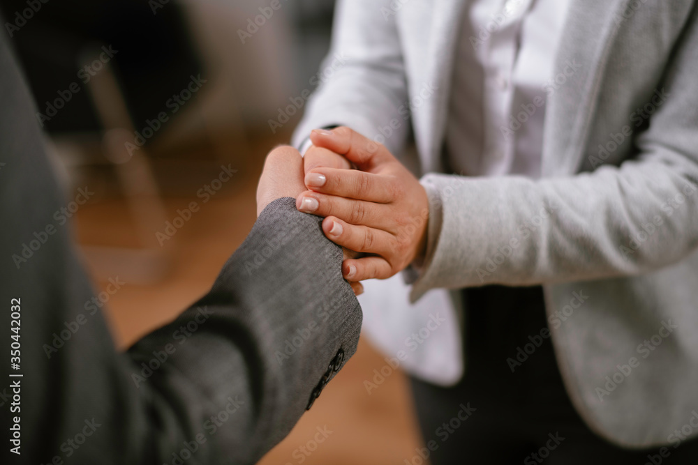 Close up of businesswoman and businessman handshake in office.	