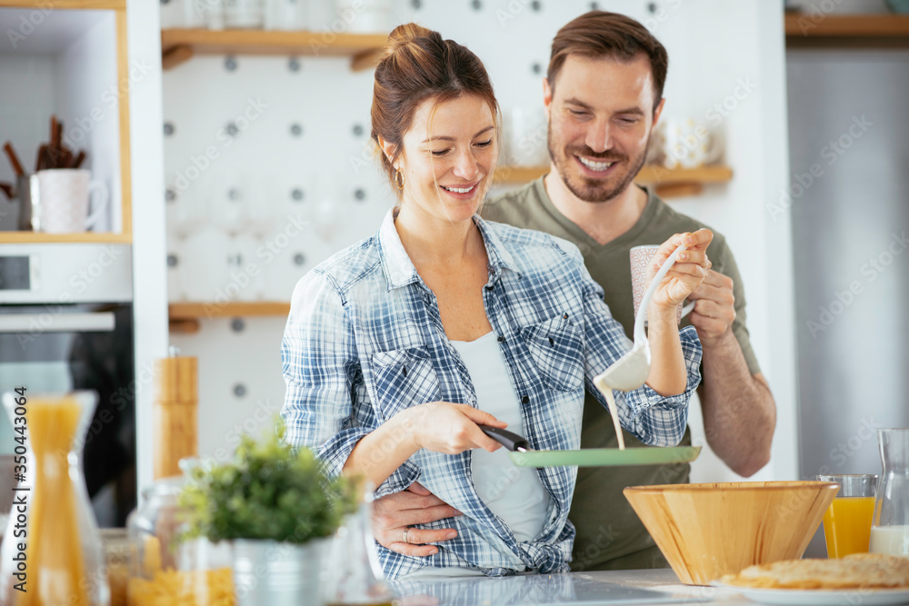 Young couple making pancakes at home. Loving couple having fun while cooking. Young couple making pancakes at home. Loving couple having fun while cooking.