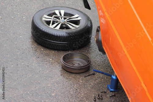 Disassembled rear axle wheel and brake drum, car repair on the road with hydraulic jack