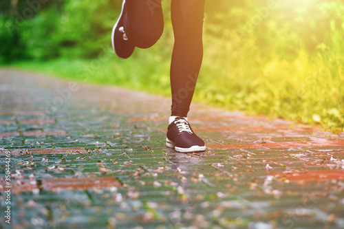 Legs of Running woman atletic spotsman trains in the summer park. Outdoor fitness portrait after rain photo