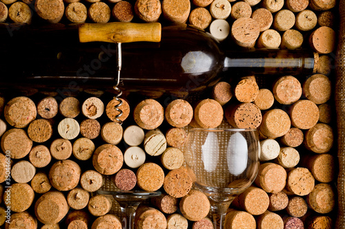Wine corks of different sizes  a corkscrew  a bottle of wine and a glass shot on an old wooden surface.