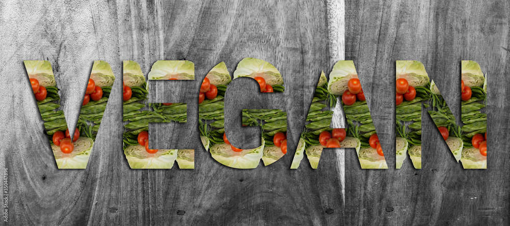 Fototapeta premium Word Vegan made from fresh vegetable cabbage, green beens, tomato and chilli on wooden Background