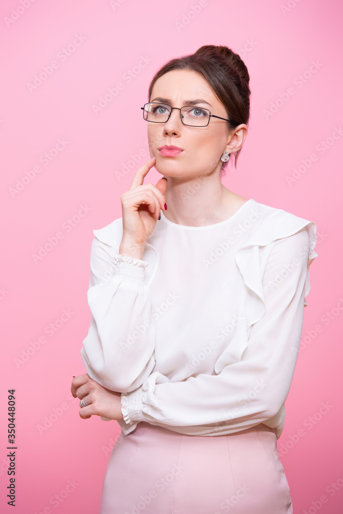 Portrait of a thoughtful business woman with glasses. Isolated on a pink background