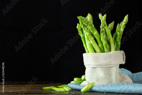 Green Asparagus in hemp sack on wood table with copy space.