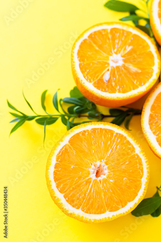 Fresh orange citrus fruit with leaves on yellow paper background. Juicy and sweet fruit. Concentration of vitamin C. Flat lay.