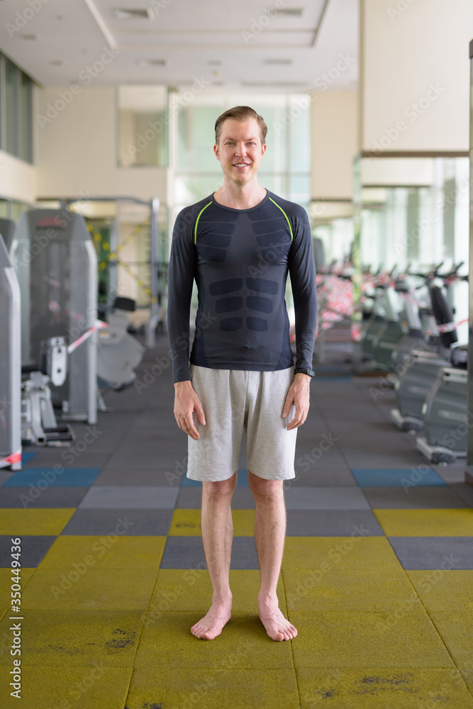 Full body shot of happy young handsome man smiling at the gym during covid-19 Full body shot of happy young handsome man smiling at the gym during covid-19
