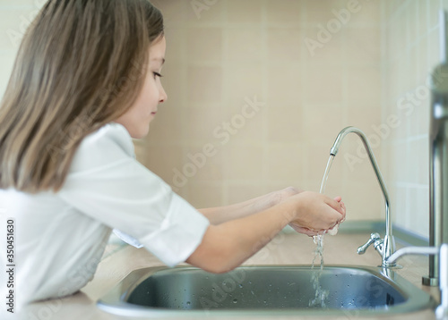 Fotografie Child pouring fresh reverse osmosis purified water in kitchen at home