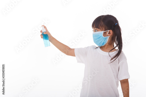 Cute Asian girl wearing a mask and washing her hands with alcohol to prevent spreading the disease on a white background. Prevention of the spread of influenza virus Coronary COVID-19 influenza