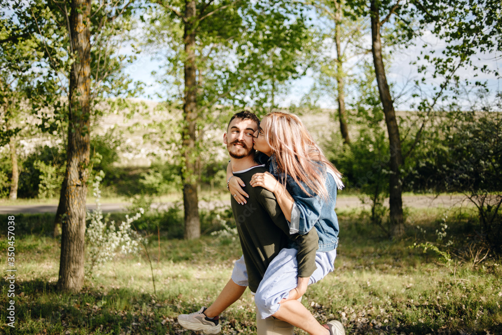 Naklejka premium Pretty girl on back of handsome guy in park.