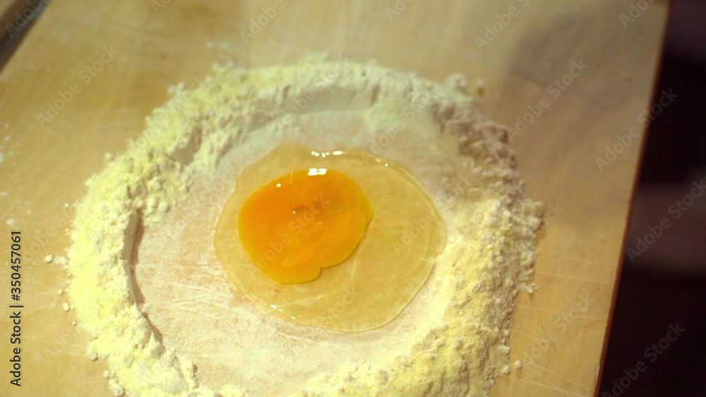 Slow Motion of chef breaking egg around flour on kitchen counter, close up of hand preparing dough - Tuscany, Italy Slow Motion of chef breaking egg around flour on kitchen counter, close up of hand preparing dough - Tuscany, Italy