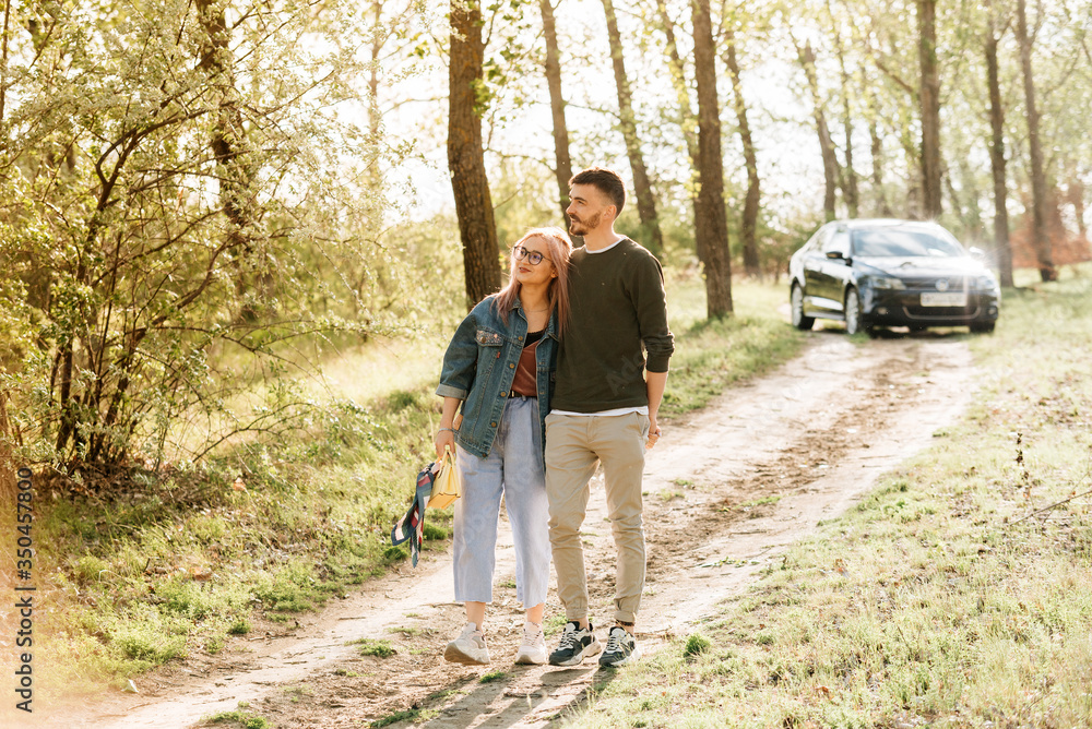 Fototapeta premium Couple walking in the woods, in the background you can see the car