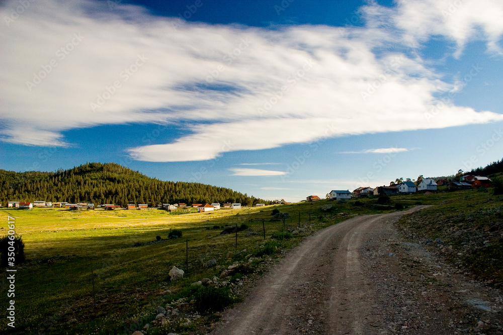 country road in the countryside, mountain landscape with blue sky and clouds