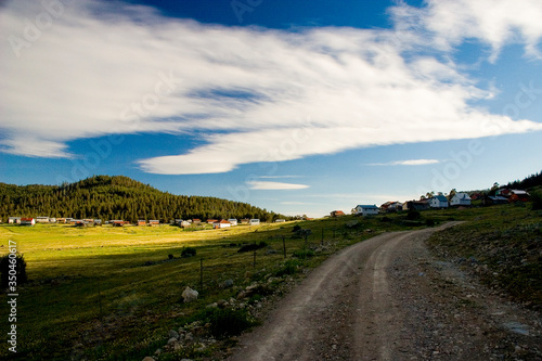 country road in the countryside, mountain landscape with blue sky and clouds