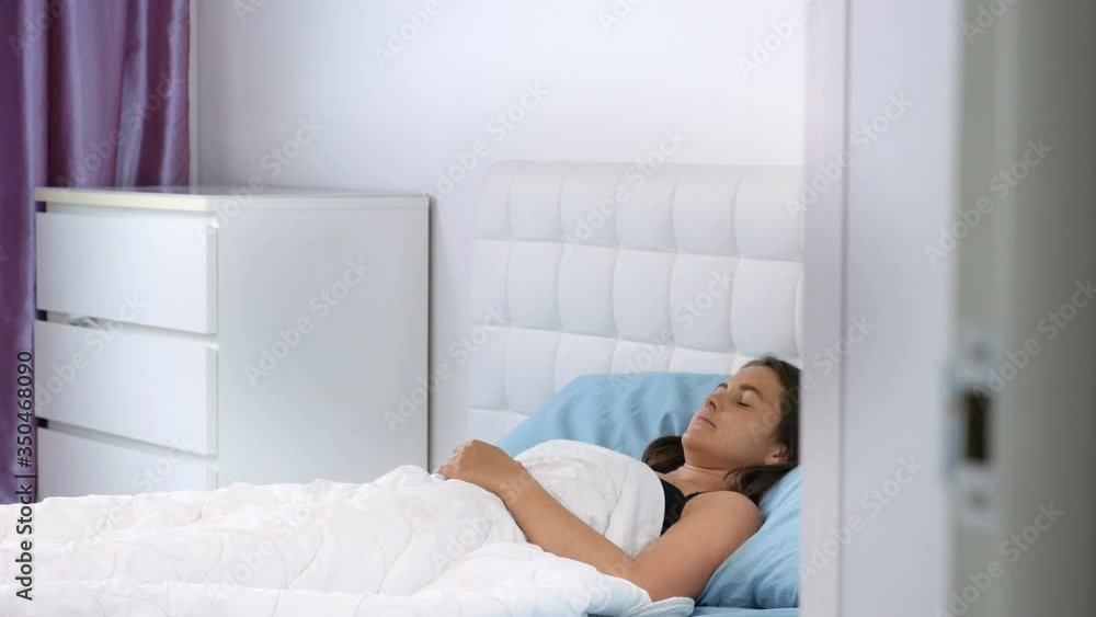 Beautiful young girl is sleeping on a white pillow. She is waking up. Calm young woman sleeping well in comfortable cozy fresh bed on soft pillow Beautiful young girl is sleeping on a white pillow. She is waking up. Calm young woman sleeping well in comfortable cozy fresh bed on soft pillow