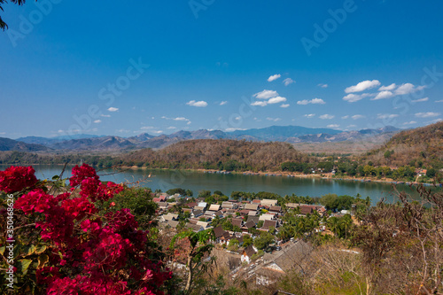 Fototapeta Naklejka Na Ścianę i Meble -  Luang Prabang old town and Mekong river, Laos, with background of ranges of mountains on a bright sunny day. The town was listed World Heritage Site by UNESCO since 1995.