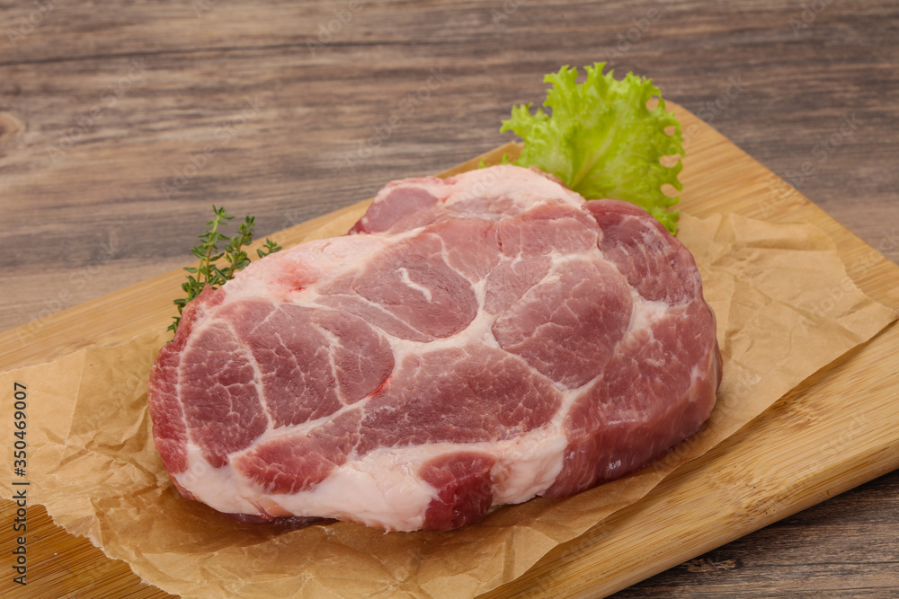 Raw pork steak over wooden board