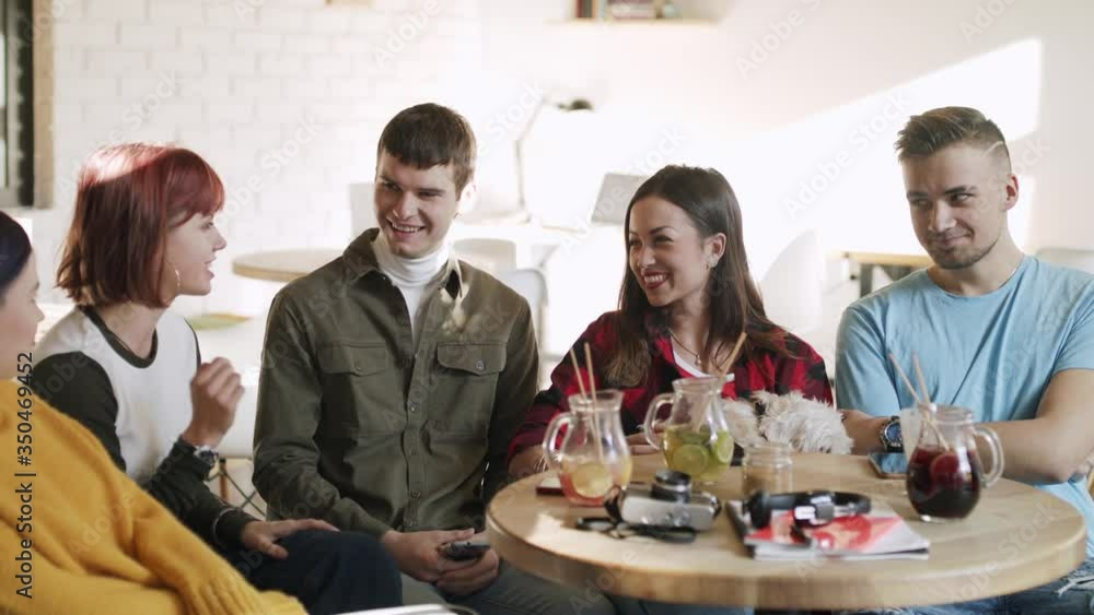 Group of young friends with pet dog sitting in cafe, talking. Slow motion. Group of young friends with pet dog sitting in cafe, talking. Slow motion.