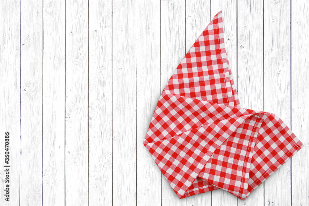 Obraz premium Red checkered folded cloth on white wooden background empty space design.