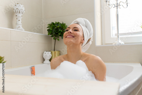 Junge Frau in der Badewanne mit viel Schaum Handtuch auf dem Kopf, Rasierer, rasiert sich die Beine, Jung, blond , schön, beauty