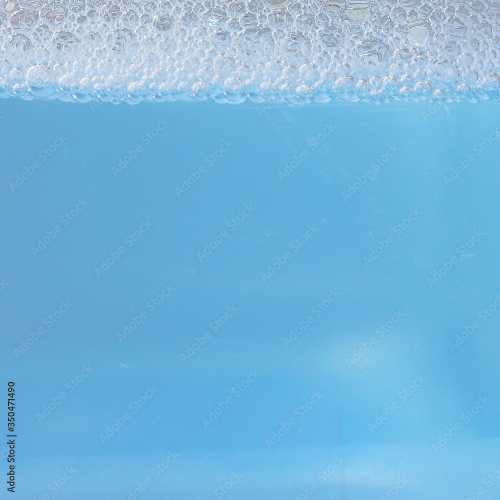 Background with soapy blue water with foam. Water level. Cleaning, Laundry.