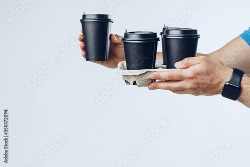 Courier hands giving packed food delivery close up against grey background