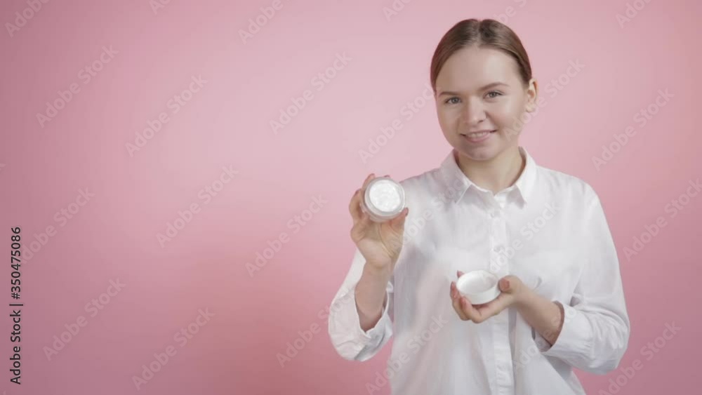 A young girl with natural beauty opens a jar of white cream. A young girl with natural beauty opens a jar of white cream.